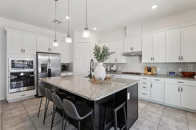 a kitchen with stainless steel appliances granite countertop a refrigerator and white cabinets