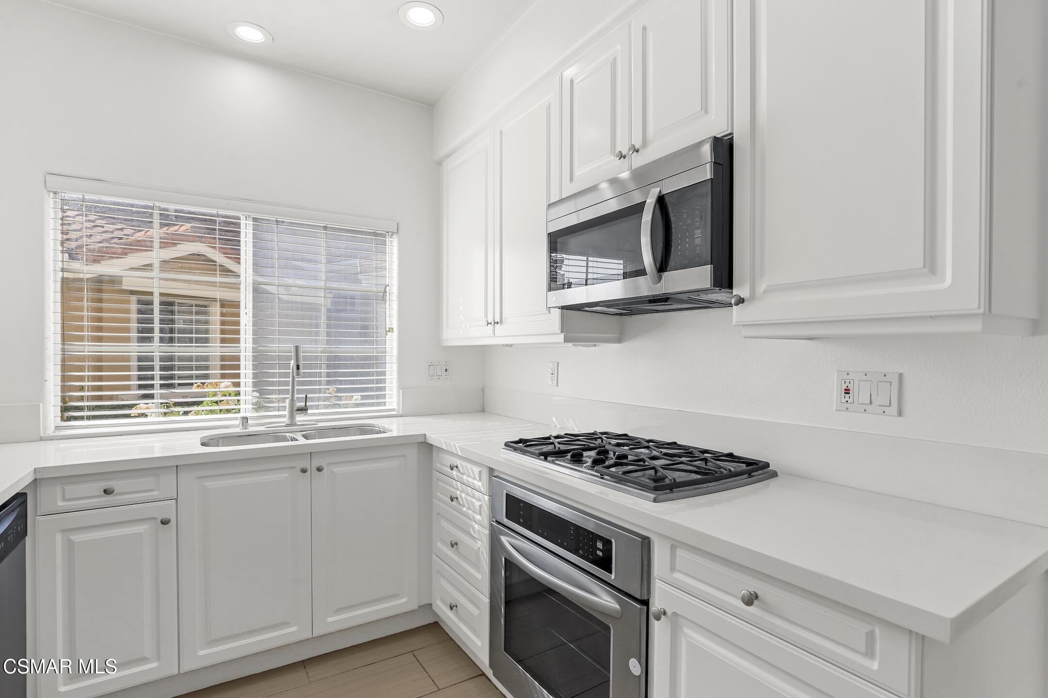 495 Novara Way Oak Park, CA 91377 - Photo 7 of 26 a kitchen with stainless steel appliances white cabinets and a stove a oven with white countertops