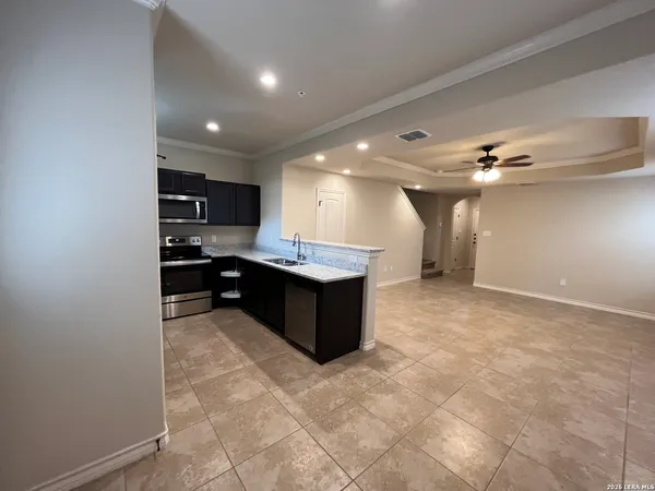a living room with stainless steel appliances kitchen island granite countertop a sink and cabinets