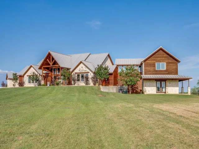 a view of a house with a big yard and large trees