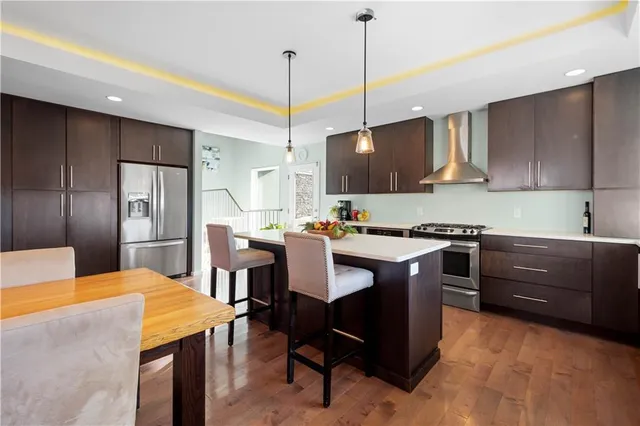 a kitchen with a refrigerator a sink a stove and chairs