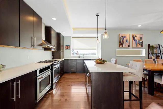 a kitchen with stainless steel appliances kitchen island granite countertop a stove a sink and a refrigerator