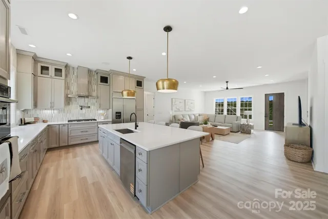 a large kitchen with stainless steel appliances a stove a sink dishwasher and a dining table with wooden floor