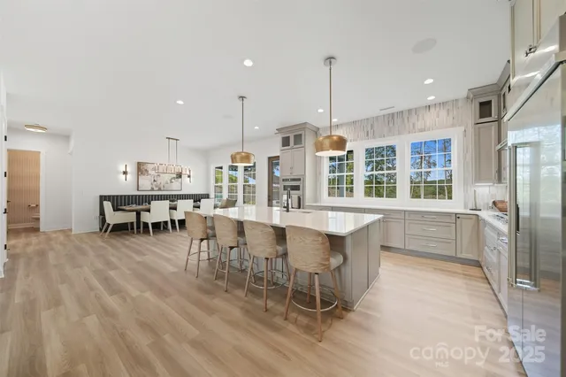 a dining hall with stainless steel appliances kitchen island granite countertop a table chairs and a view of living room