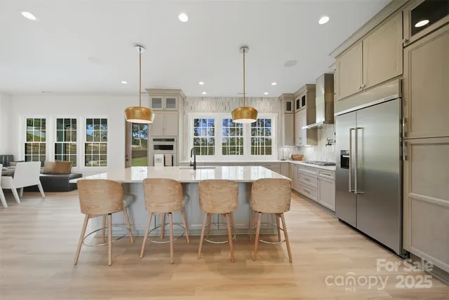 a kitchen with stainless steel appliances kitchen island granite countertop a refrigerator and chairs