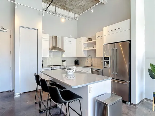 a kitchen with stainless steel appliances a refrigerator a stove a sink and white cabinets with wooden floor