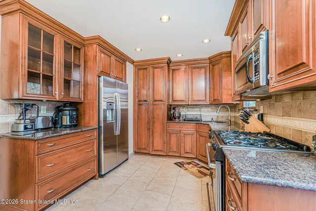 a kitchen with stainless steel appliances granite countertop a refrigerator and wooden cabinets