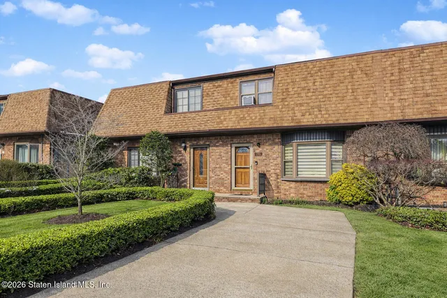 a front view of a house with a yard and potted plants