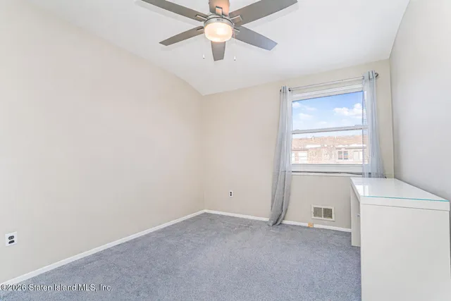 a view of empty room with window and ceiling fan