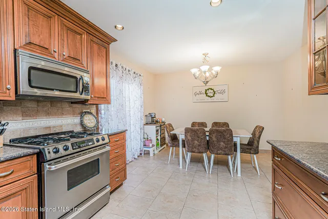 a kitchen with stainless steel appliances granite countertop a stove top oven a sink dishwasher a dining table and chairs with wooden floor