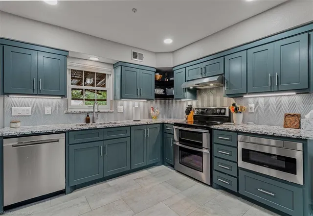 a kitchen with stainless steel appliances granite countertop a stove sink and cabinets