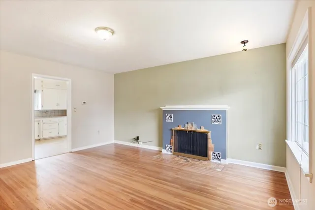a view of empty room with wooden floor and fireplace