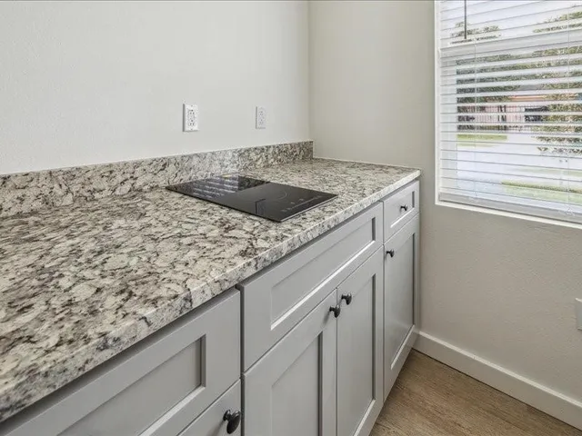 a utility room with granite countertop white cabinets and a sink