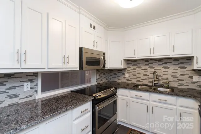a kitchen with granite countertop white cabinets and stainless steel appliances
