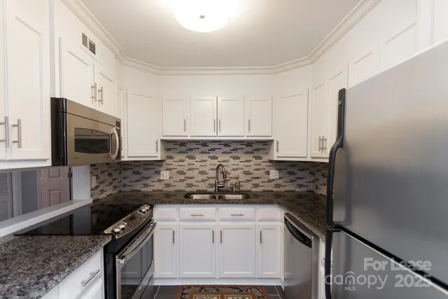 a kitchen with granite countertop a sink stove and microwave