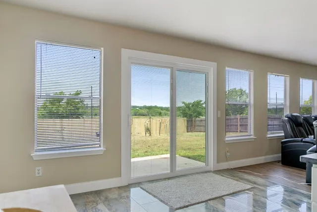a view of an empty room with wooden floor and windows