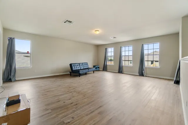 a view of an empty room with a window and wooden floor