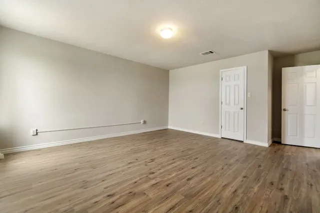 a view of an empty room with wooden floor