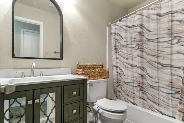 a bathroom with a granite countertop sink a toilet and a mirror