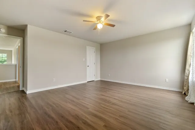 an empty room with wooden floor and fan