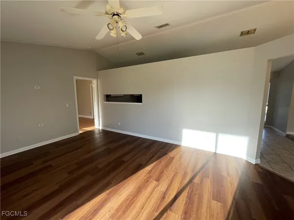 a view of an empty room with wooden floor and a window