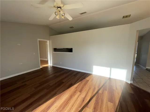 a view of an empty room with wooden floor and a window