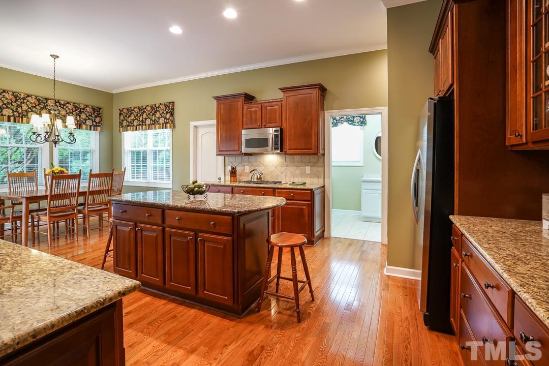 2920 Elmfield Street Raleigh, NC 27614 - Photo 9 of 30 The open and well lit kitchen features rich wood cabinets and granite counters. The door to the left of the cooktop is a large walk-in pantry.