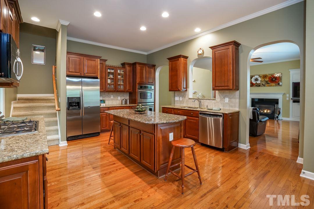 2920 Elmfield Street Raleigh, NC 27614 - Photo 10 of 30 Stainless appliances including double ovens, microwave, dishwasher, and double sink with garbage disposal. Gas cooktop. Back stairs from kitchen to upstairs hallway.