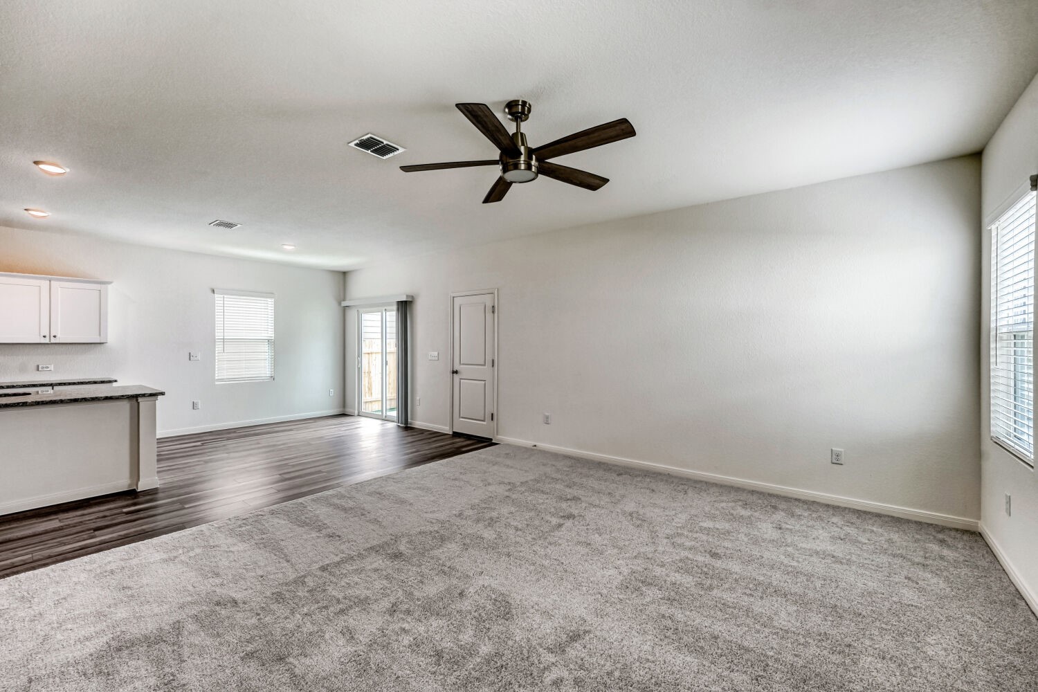 124 Mullen Way Taylor, TX 76574 - Photo 17 of 22 Open-concept living area featuring a ceiling fan, light gray carpeting, and wood-finish flooring