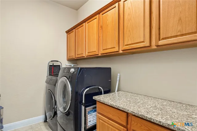 a utility room with granite countertop cabinets washer and dryer