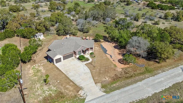 an aerial view of a house with a yard and trees all around