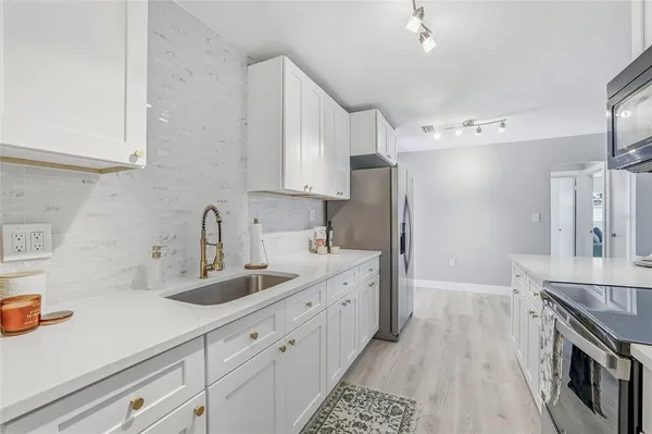 a kitchen with stainless steel appliances a sink dishwasher stove refrigerator and cabinets