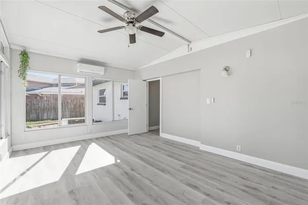 a view of an empty room with a window and wooden floor