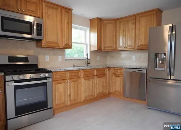 a kitchen with stainless steel appliances granite countertop a refrigerator stove and microwave