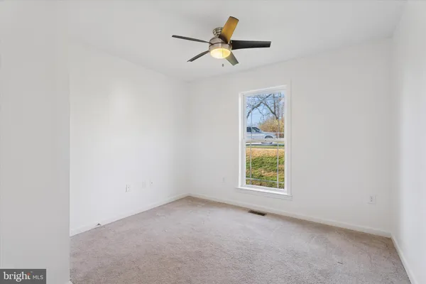 an empty room with a window and a ceiling fan