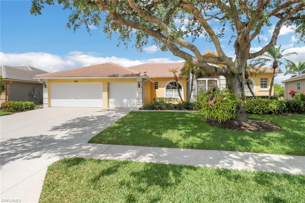 3283 Potomac Court Naples, FL 34120 - Photo 1 of 29 View of front facade featuring a tiled roof, an attached garage, concrete driveway, a front lawn, and stucco siding