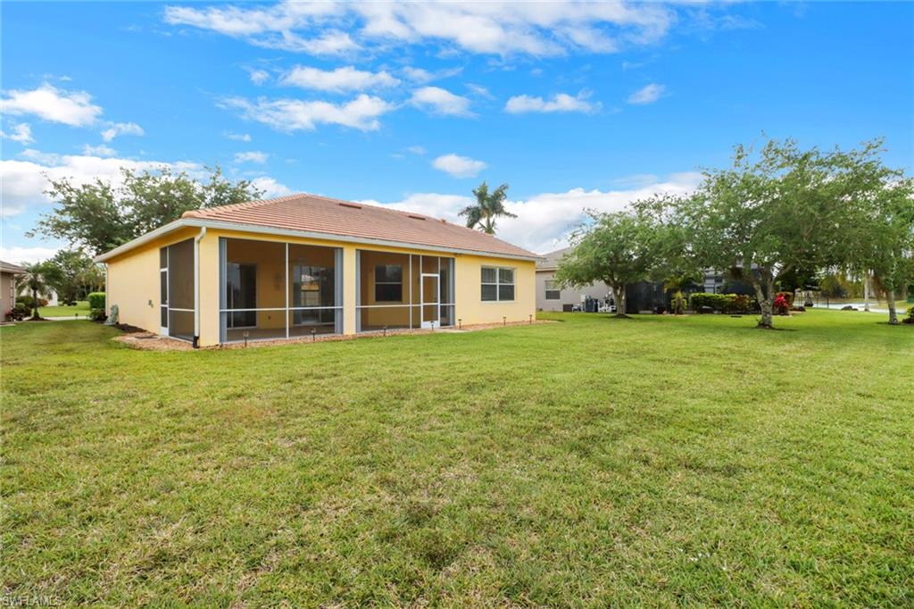 3283 Potomac Court Naples, FL 34120 - Photo 24 of 29 Rear view of property featuring a lawn, stucco siding, a sunroom, and a tiled roof