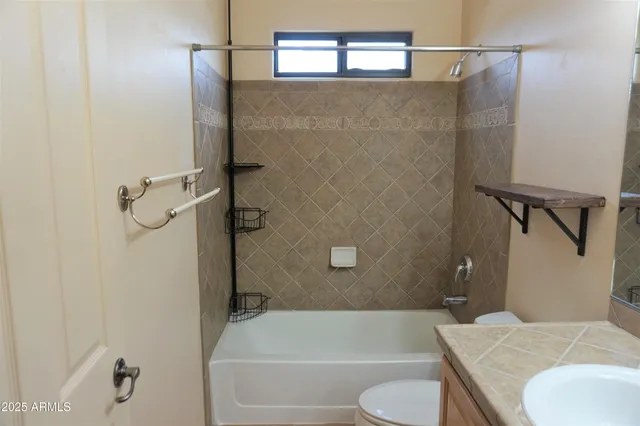 a bathroom with a granite countertop bathtub shower and toilet