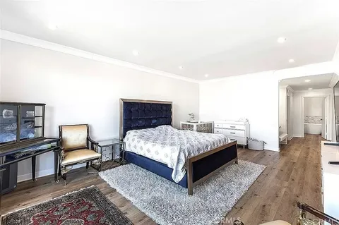 a spacious bedroom with a bed and wooden floor