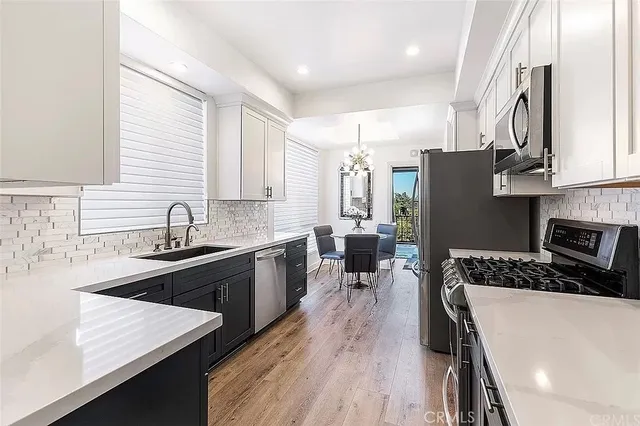 a kitchen with stainless steel appliances granite countertop a sink stove refrigerator and wooden floor