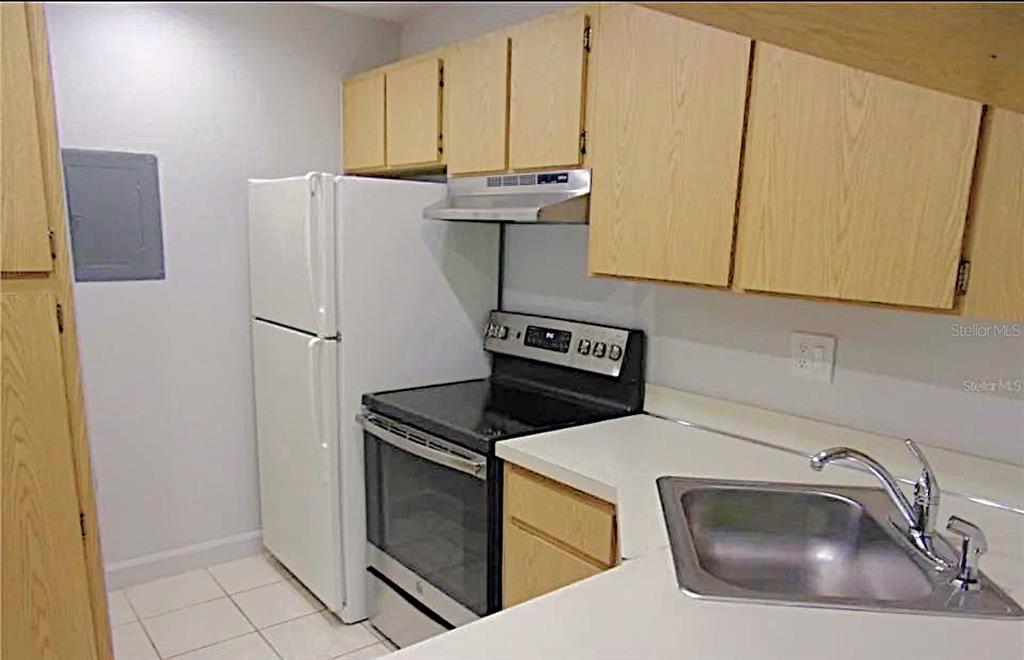 1344 Pine Ridge Circle East, Unit E3 Tarpon Springs, FL 34688 - Photo 2 of 25 a kitchen with a sink a refrigerator and cabinets