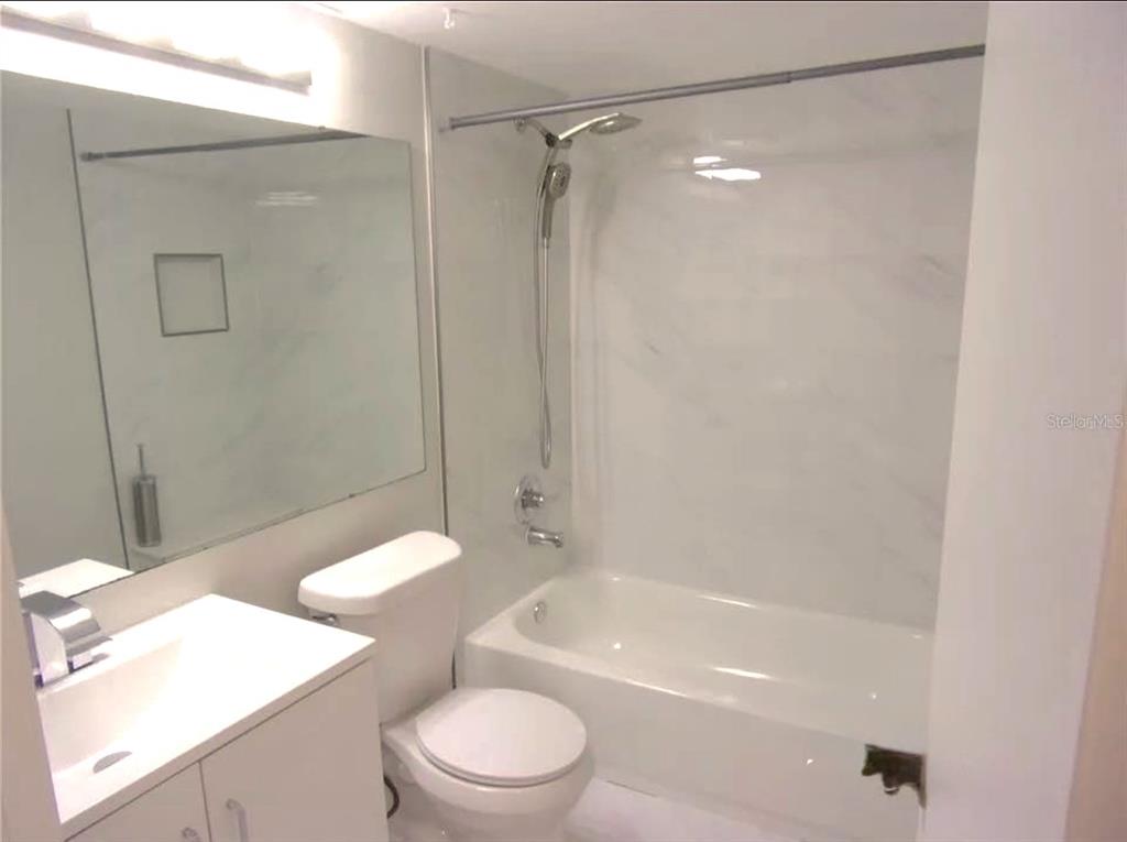 1344 Pine Ridge Circle East, Unit E3 Tarpon Springs, FL 34688 - Photo 8 of 25 a bathroom with a granite countertop bathtub shower sink vanity and toilet