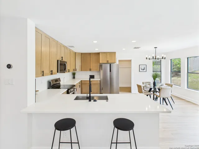 a kitchen with stainless steel appliances a dining table chairs and a refrigerator