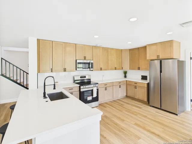a kitchen with granite countertop a refrigerator stove top oven and sink
