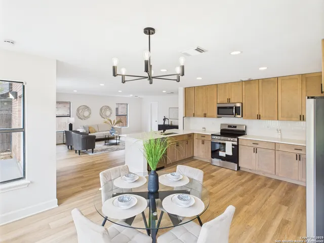 a kitchen with stainless steel appliances granite countertop a refrigerator a stove top oven a sink dishwasher and white cabinets with wooden floor