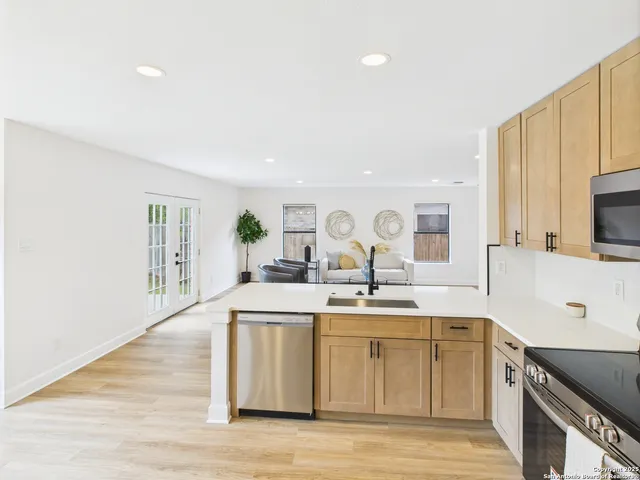 a view of a kitchen with kitchen island a sink wooden floor and counter top space
