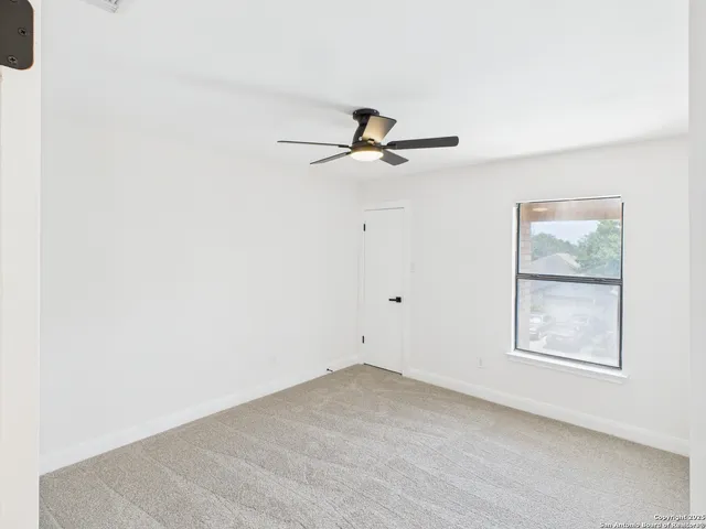 an empty room with windows and fan