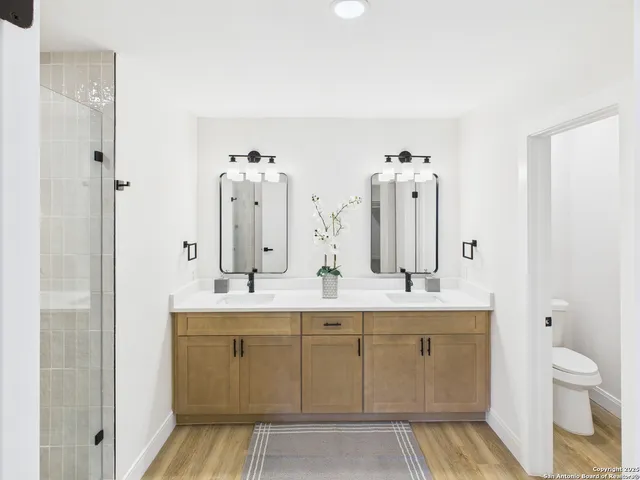 a spacious bathroom with a double vanity sink toilet and shower