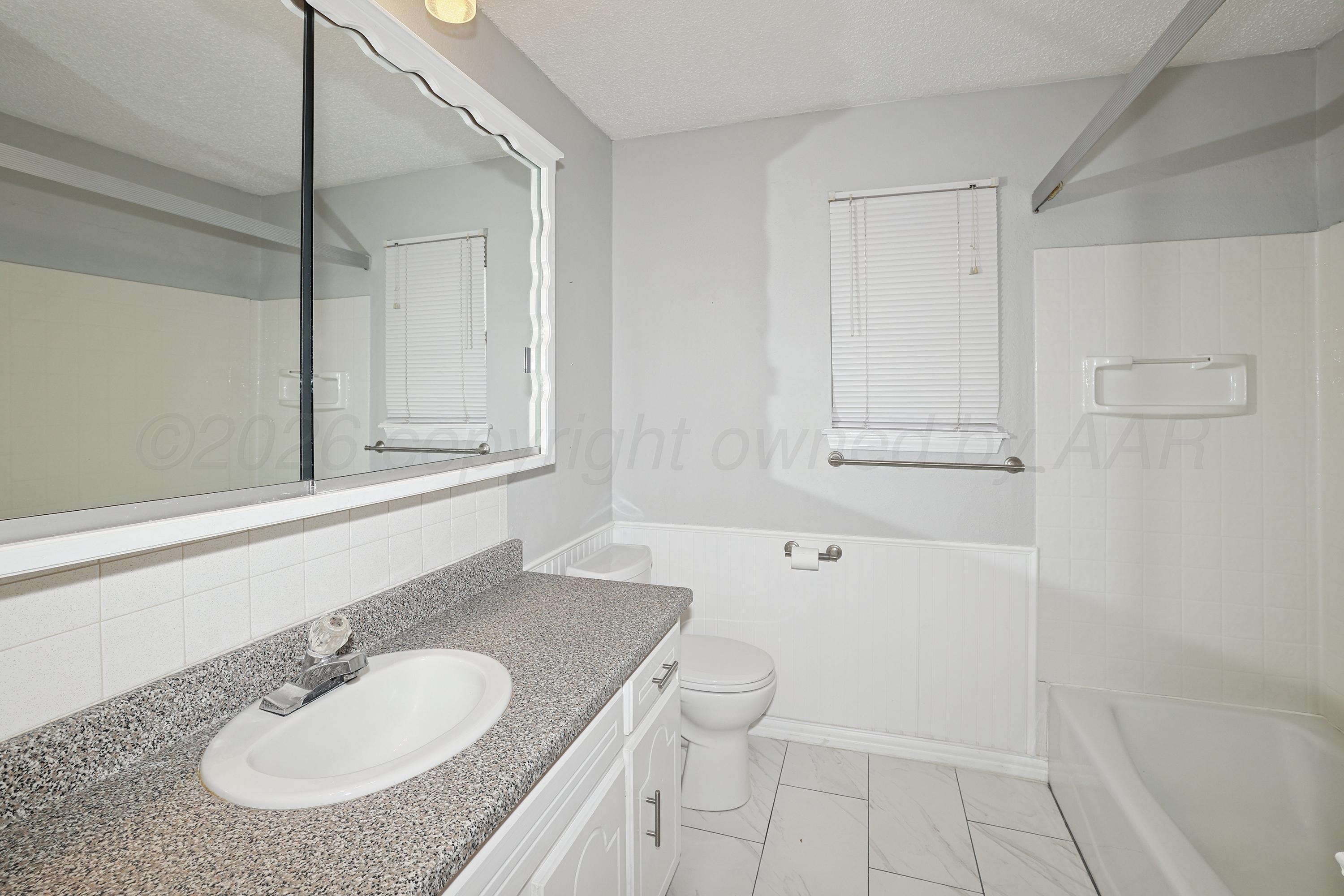 6108 Cornell Street Amarillo, TX 79109 - Photo 19 of 26 a bathroom with a granite countertop sink toilet and shower
