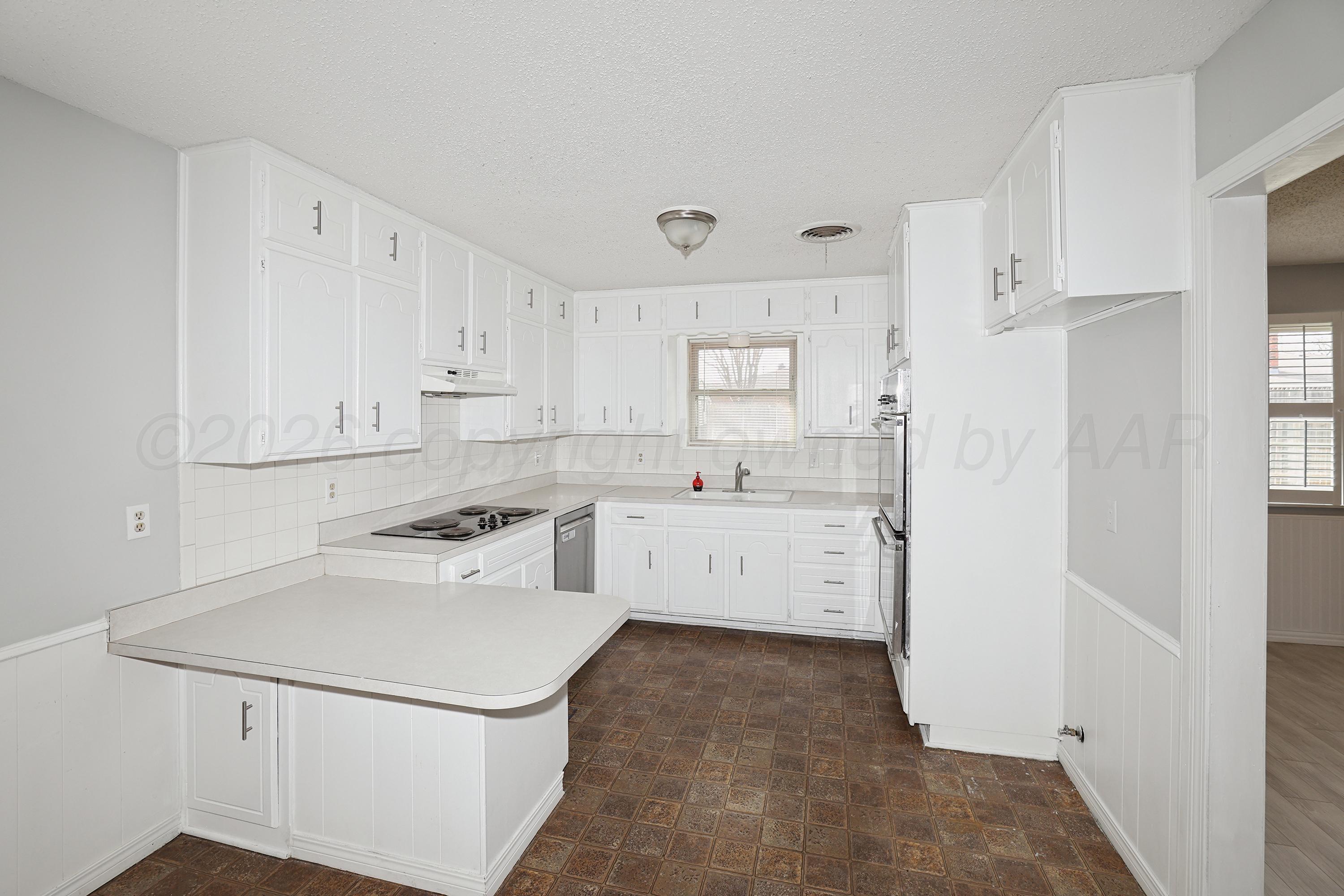 6108 Cornell Street Amarillo, TX 79109 - Photo 10 of 26 a kitchen with white cabinets sink and white appliances